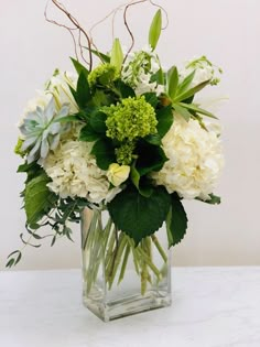 a vase filled with white flowers and greenery