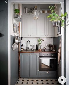 a kitchen with an oven, sink and potted plant in the doorway to another room