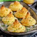 small pastries on a plate with parmesan sprinkles and green onions