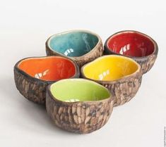 four bowls with different colors in them on a white surface