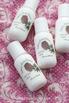 four bottles of body lotion sitting on top of a pink and white tablecloth