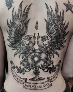 the back of a man's chest with two birds and an emblem on it