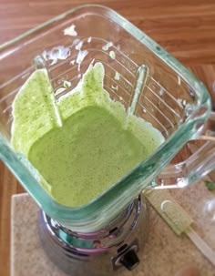 a blender filled with green liquid on top of a wooden table