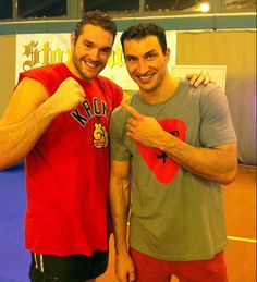 two men standing next to each other giving thumbs up