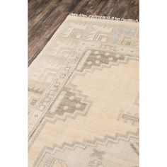 a beige rug with an intricate design on the top and bottom, sitting on a wooden floor