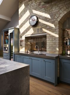 a kitchen with a large clock on the wall above it's counter top and sink