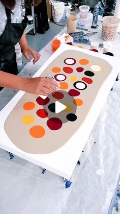 a woman is making an art project with circles on a large sheet of paper and paint