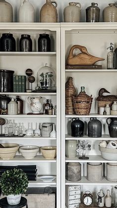 an open bookcase filled with lots of vases and other items on top of it