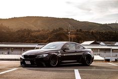 a black sports car parked in a parking lot next to a mountain and some buildings