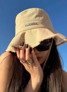 a woman wearing a tan hat and sunglasses holding her hands to her face while she covers her eyes