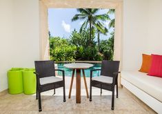 two chairs and a table in front of an open window with a pool behind them