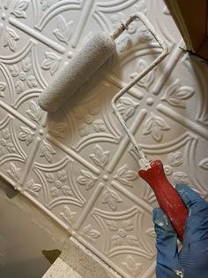 a person using a paint roller to paint a wall with decorative tiles on the walls