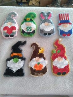 cross stitch christmas ornament designs on a white towel with other ornaments in the background