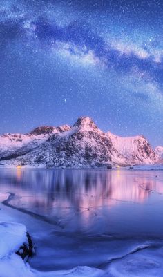 the night sky is lit up with stars above mountains and water, while snow covers the ground