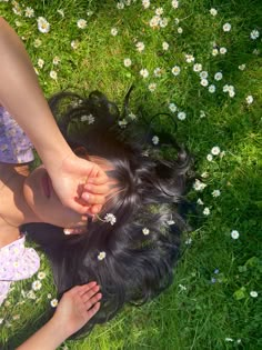 a woman laying on top of a lush green field next to a flower filled field