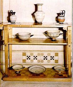 a shelf with bowls and vases on top of it in a room that has tile flooring