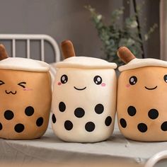 three coffee mugs with faces painted on them sitting on a table in front of a bed