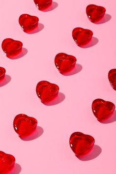 many red hearts on a pink surface with water droplets in the shape of heart shapes