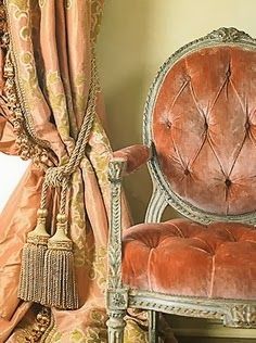 an old fashioned chair sitting in front of a window with drapes and curtains behind it