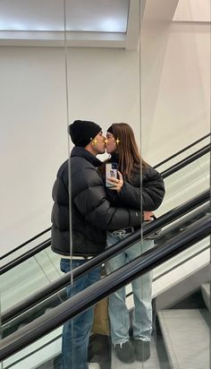 a man and woman kissing on an escalator