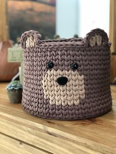 a knitted bear basket sitting on top of a wooden table