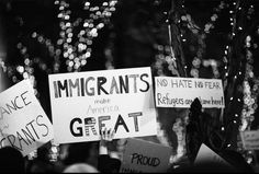 many people holding signs and protesting against immigrant rights in front of christmas lights at night