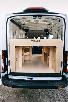 the back end of a van with its doors open and empty desks in it