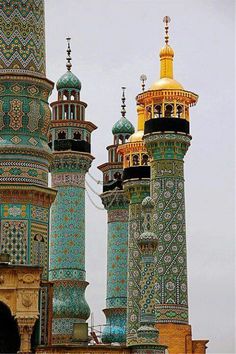 two tall buildings with gold and blue decorations on top of each other in front of a cloudy sky