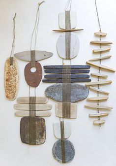 a group of different shapes and sizes of objects hanging from strings on a white wall