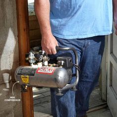 a man standing next to an open door with a small air compressor on it's side