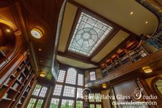 the inside of a library with lots of bookshelves and stained glass windows in it