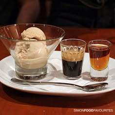 three different types of ice cream on a white plate with spoons and two glasses