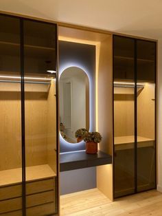 an empty closet with wooden shelves and glass doors on the door is illuminated by a round mirror