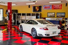 a white sports car parked in a garage with red and black checkered flooring