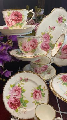 a table topped with plates and cups covered in pink flowered designs on white dishes