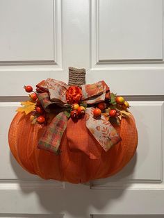 an orange pumpkin decorated with fall leaves and bows