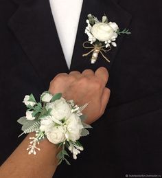 two grooms holding hands with white flowers and greenery on their lapel covers