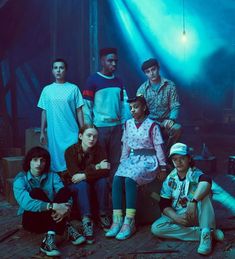 a group of young people sitting on the ground in front of a blue light with their arms around each other