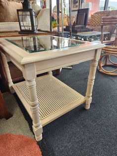 a white coffee table with glass top on carpeted flooring in front of furniture