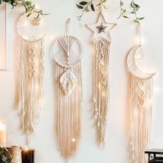 three dream catchers hanging on the wall next to a candle and some greenery