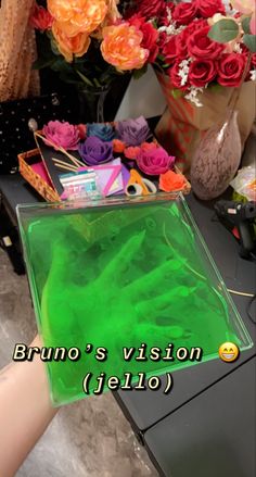 a person holding a green bag with flowers in the background and text that reads, brunio's vision jello