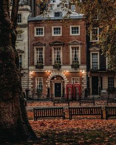 an old brick building with many windows and balconies in the fall leaves on the ground