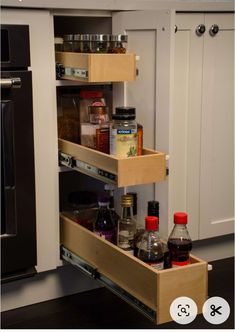 an open cabinet with spices and condiments in the bottom drawer, next to a stove