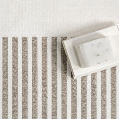 an empty dish sitting on top of a striped tablecloth