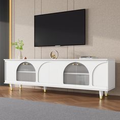 a white entertainment center with gold accents and a flat screen tv mounted on the wall