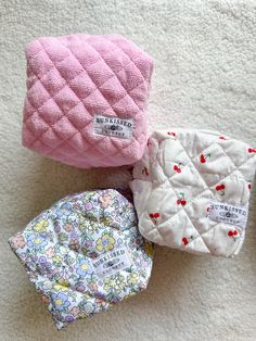 three baby bibs laying on the floor next to each other, one pink and one white