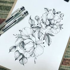 a drawing of some flowers on a piece of paper with two pens next to it