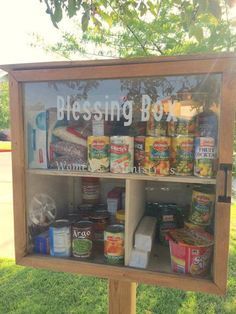 a display case with canned food in it on the side of a road next to grass