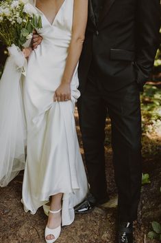 a bride and groom standing together in the woods