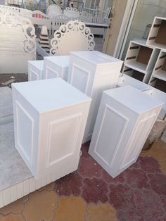 four white cabinet doors sitting next to each other on top of a stone slab in front of a building